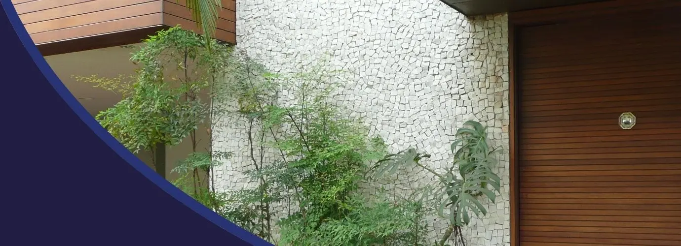Parede externa revestida em mosaico português branco, ao lado de um jardim